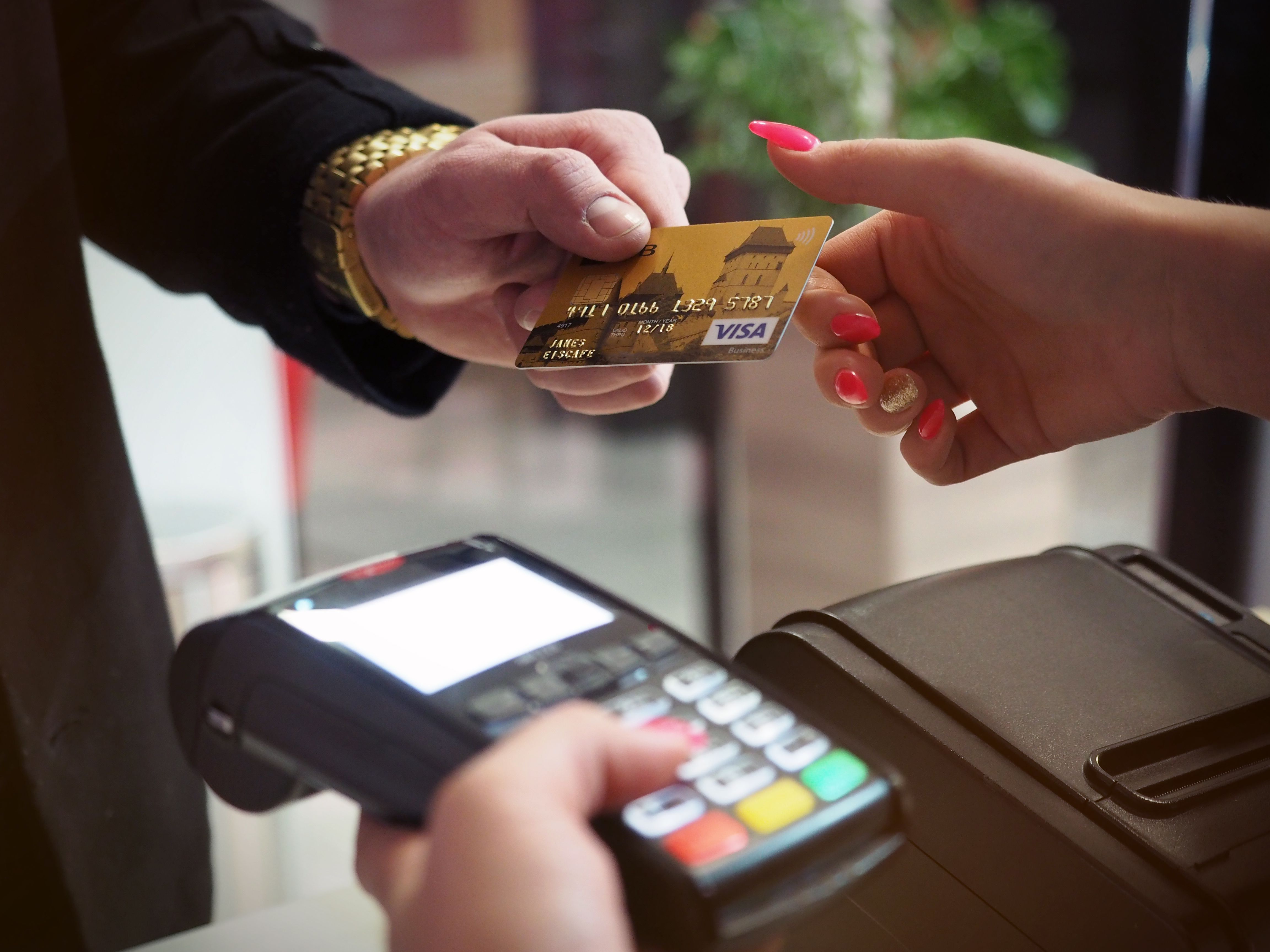 Photo of a person paying with a card using a hand-held terminal